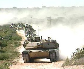 An armoured column of M1A1 Abrams Tanks and M2 Bradley IFVs move down a dirt road outside the city of Mogadishu, Somalia.